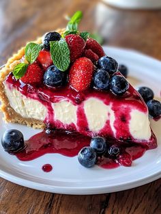 a piece of cheesecake with berries and blueberries on top sits on a white plate