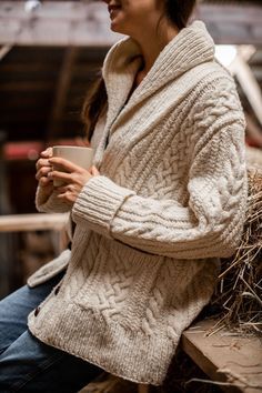 a woman sitting on top of a wooden bench holding a cup