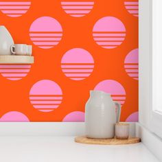 an orange and pink polka dot wallpaper with white vases on the counter next to it