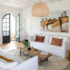 a living room with white furniture and paintings on the wall