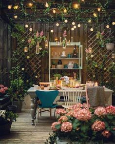 an outdoor dining area with potted plants and lights hanging from the ceiling above it