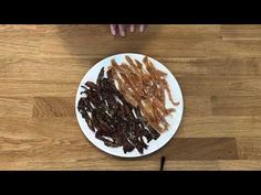 a plate full of bacon on a wooden table with someone's hand reaching for it