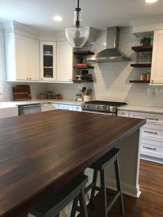 a kitchen with white cabinets and wooden counter tops, along with an island in the middle