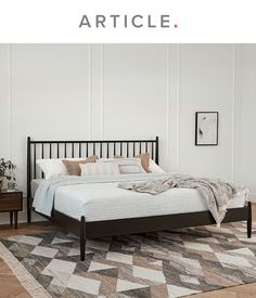 a bed sitting on top of a wooden floor next to a white wall in a bedroom