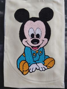 a mickey mouse embroidered on top of a white bag with blue and yellow trimmings