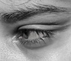 black and white photograph of an eye with long eyelashes, looking down at the camera