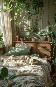 an unmade bed with green plants hanging from the ceiling