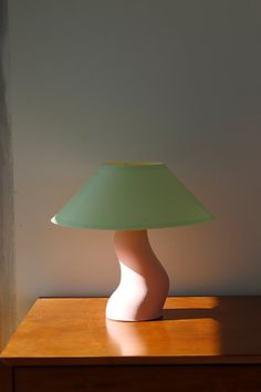 a lamp sitting on top of a wooden table next to a white and green shade