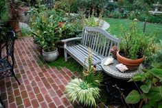 a bench sitting in the middle of a garden filled with potted plants and flowers