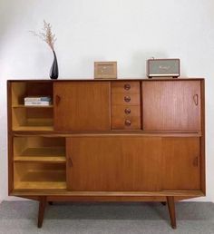 a wooden cabinet with drawers and shelves next to a vase