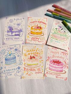 four birthday cards with colored pencils on top of them and one has a cake