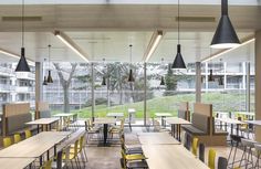 an empty cafeteria with tables and chairs in front of large windows that look out onto a grassy area