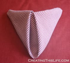 a red and white checkered cloth folded into a triangle shape with the words quick and easy napkin fold technique