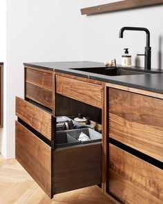 an open drawer in the middle of a kitchen counter top next to a sink and cabinets