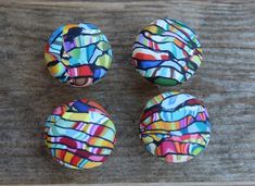 four brightly colored buttons sitting on top of a wooden table