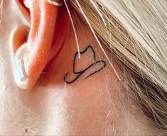 a woman's ear with a heart tattoo on it