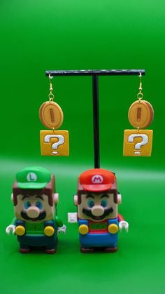 two toy figures are standing next to each other on a green background, one has a question mark in it's ear