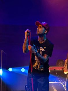 a man standing on top of a stage holding a microphone in front of two other people