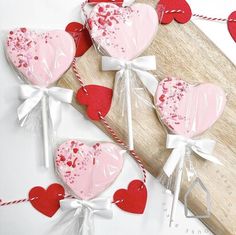 three heart shaped lollipops tied up on a cutting board with hearts attached to them