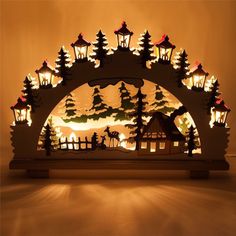 a lit up christmas scene in the shape of an arch with trees and houses on it