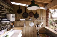 an outdoor kitchen with pots and pans hanging from the ceiling