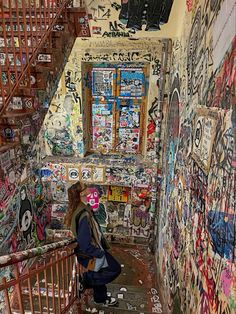 a woman is standing on the stairs in an alleyway with graffiti all over it