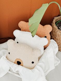 two stuffed animals sitting on top of a bed next to a basket with a plant in it