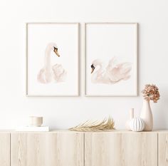 two swans are hanging on the wall above a dresser with vases and other items