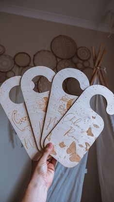 a hand holding five wooden baby bibs