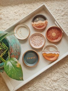 a tray that has some plates on top of it and a potted plant in the middle