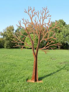 a metal tree sculpture sitting in the middle of a field