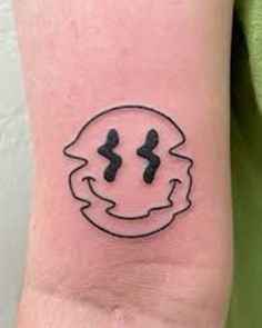 a small tattoo on the wrist of a person's arm with two faces drawn in black ink