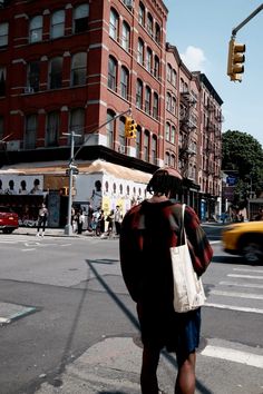 a man walking across a street next to tall buildings