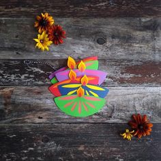 colorful paper flowers on wooden planks next to an ornament shaped like a flower