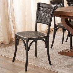 a dining room table with four chairs and a rug on the floor in front of it