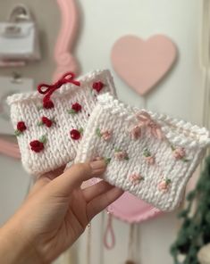 two hand knitted pieces of cloth with roses on them, one is white and the other is pink