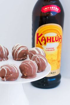 chocolate covered doughnuts on a white plate next to a bottle of kahlua