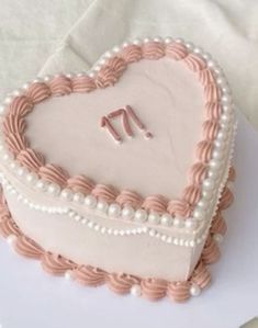 a heart shaped cake decorated with pearls and icing on a white tableclothed surface