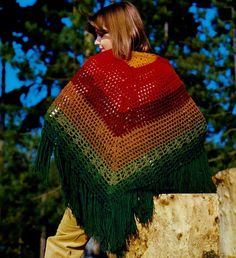 a woman wearing a red, green and yellow ponchy with fringes on it