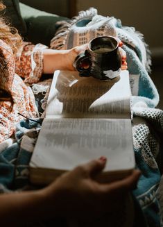 a woman reading a book and holding a coffee mug