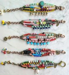 six beaded bracelets are lined up on a marble surface