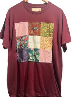 a t - shirt hanging on a wooden hanger with an image of flowers and leaves