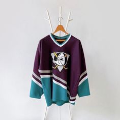 a hockey jersey hanging on a rack with clothes hanger in front of the wall