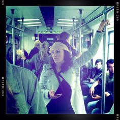 a woman standing on a bus with her arms in the air and other people behind her