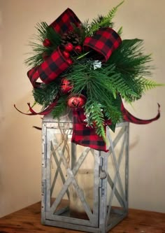 a lantern with christmas decorations and greenery in it