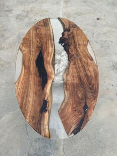 a table made out of wood and glass in the shape of an oval with two faces