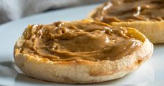 two pieces of bread with peanut butter spread on them sitting on a white plate next to a blue towel