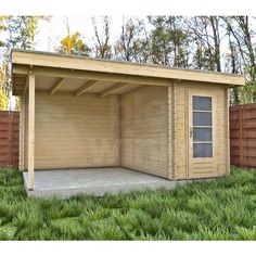 a wooden shed sitting in the grass next to a fence