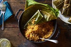 some food is in a pot on a table with plates and silverware next to it