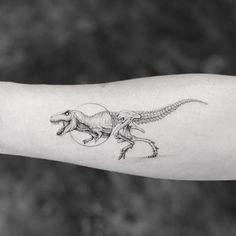 a small dinosaur tattoo on the arm